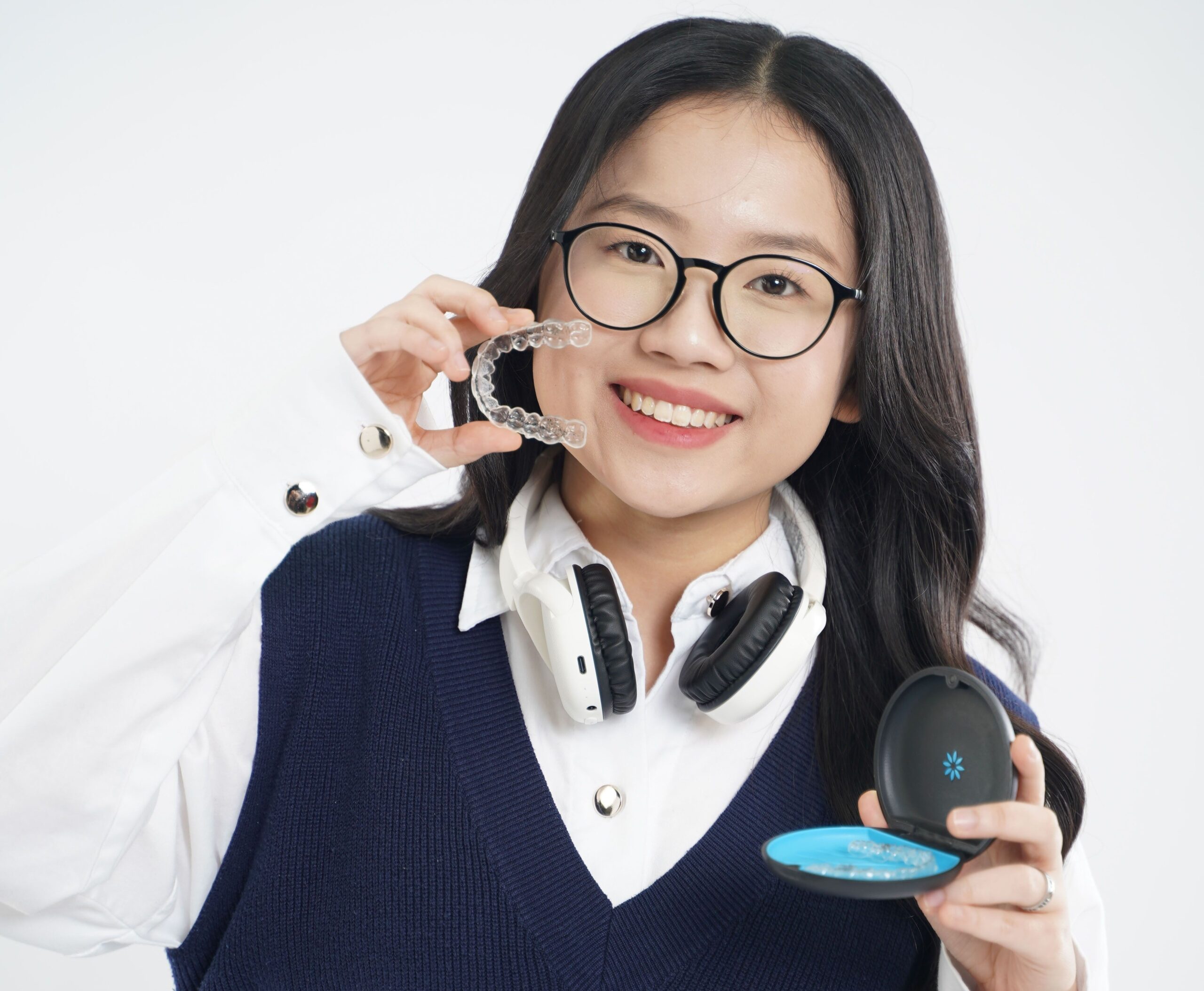 Smiling woman holding clear Invisalign aligners in Fort Mill, Steele Creek, and Charlotte, NC.